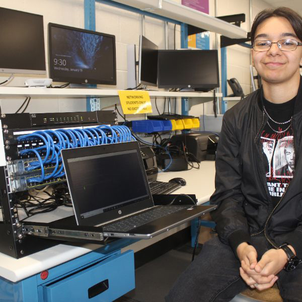  student next to computer equipment
